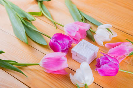 Beautiful bouquet of tender pink and white tulips with colorful gift box on light wooden backgroundの写真素材