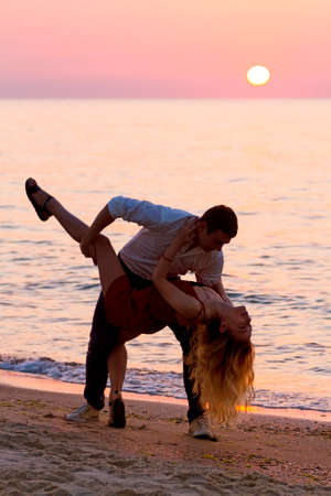 Young couple dancing on seaside at sunrise.の写真素材