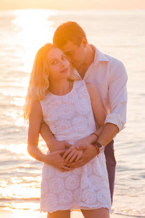 Young romantic couple on seaside at golden sunrise.の写真素材