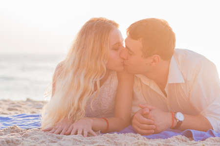 Young couple kissing on seaside at golden sunrise.の写真素材