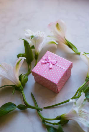 Pink gift box surrounded with alstroemeria flowers on marble surface. Spring composition. Springtime. Mother`s day card.の写真素材