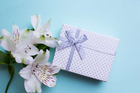White gift box with alstroemeria flowers on pastel blue background. Spring composition. Springtime. Mother`s day card.の写真素材