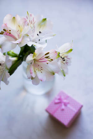 Beautiful tender bouquet of white Alstroemeria with pink gift box on table. Spring composition. Springtime. Mother`s day card.の写真素材