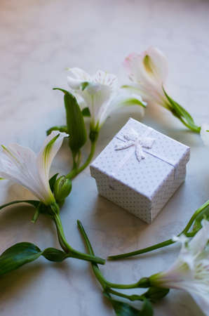 White gift box surrounded with alstroemeria flowers on marble surface. Spring composition. Springtime. Mother`s day card.の写真素材