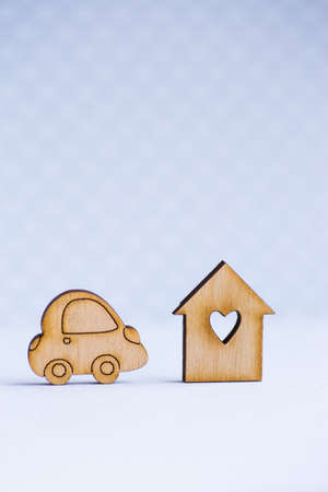 Wooden house with hole in form of heart with wooden car icon on gray background. Concept of moving or traveling.の写真素材