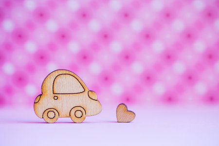 Wooden car icon with little heart on pink spotted background. Concept of romantic trip. Symbol of traveling.の写真素材