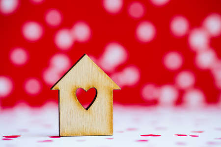 Wooden house with hole in form of heart on red and white spotted background.の写真素材
