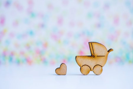 Wooden icon of baby buggy and little heart on colorful background. Sign of baby carriage. Symbol of childbirth.の写真素材