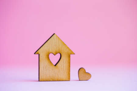 Wooden house with hole in form of heart with little heart on pink background.の写真素材