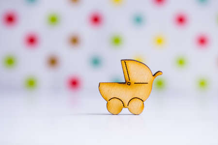 Wooden icon of baby buggy on colorful spotted background. Sign of baby carriage. Concept of childbirth.の写真素材