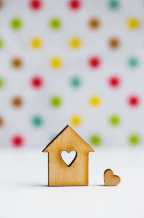 Wooden house with hole in form of heart with little heart on colorful spotted backgroundの写真素材