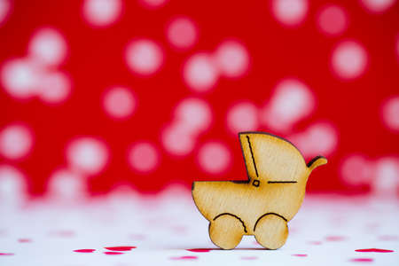 Wooden icon of baby buggy on red and white spotted background. Sign of baby carriage. Concept of childbirth.の写真素材