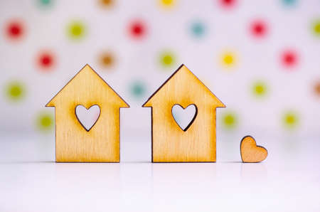 Two wooden houses with hole in form of heart with little heart on colorful spotted backgroundの写真素材