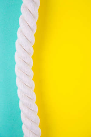 Sea rope on colored mint green and yellow backgrounds with negative space. Minimalistic colorful summer background. Top view. Flat lay in marine style.の写真素材