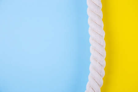 Sea rope on colored yellow and blue backgrounds with negative space. Minimalistic colorful summer background. Top view. Flat lay in marine style.の写真素材