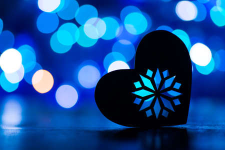 Silhouette of heart with garland lights on blue bokeh background.の写真素材