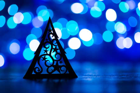 Silhouette of Christmas tree with starry ornament with garland lights on blue bokeh backgroundの写真素材