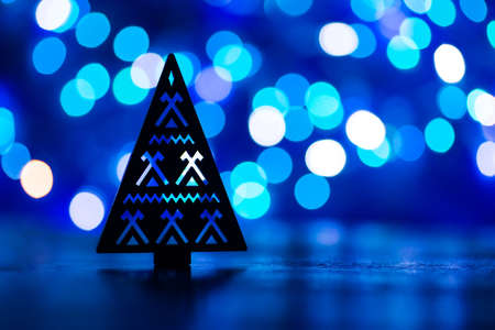 Silhouette of Christmas tree with ornament with garland lights on blue bokeh backgroundの写真素材