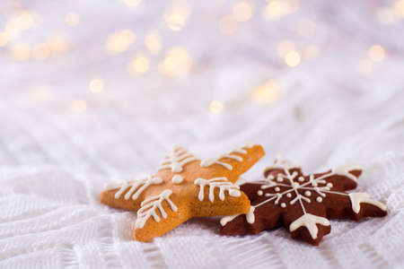 Christmas glazed cookie in form of star and snowflake on light and warm bokeh background. New year card. Xmas sweets.の写真素材