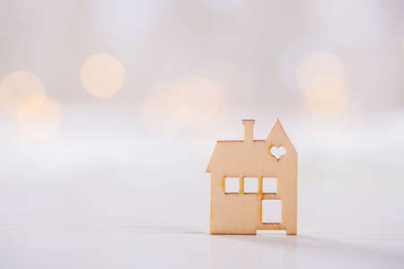 Wooden icon of house with hole in the form of heart on light bokeh background. Romantic card. Concept of sweet home.の写真素材