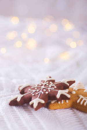 Christmas glazed cookie in form of star and snowflake on light and warm bokeh background. New year card. Xmas sweets.の写真素材