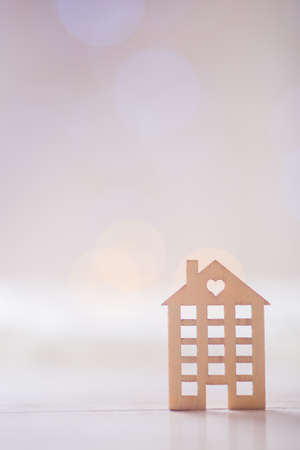 Wooden icon of house with hole in the form of heart on light bokeh background. Romantic card. Concept of sweet home.の写真素材