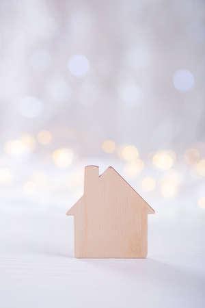 Wooden icon of house on light bokeh background. Concept of sweet home.の写真素材