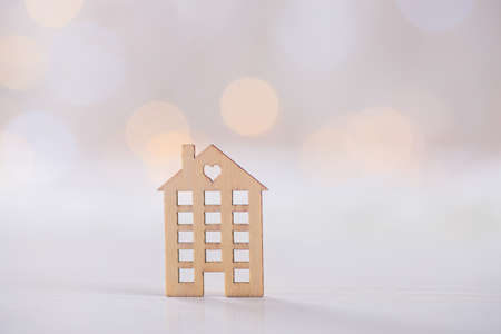 Wooden icon of house with hole in the form of heart on light bokeh background. Romantic card. Concept of sweet home.の写真素材
