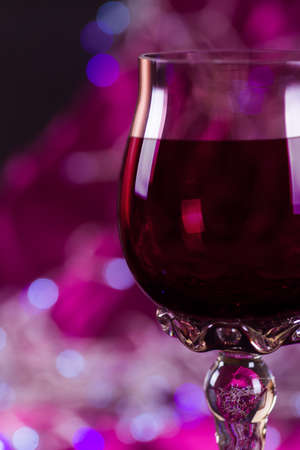 Openwork glass of red wine on pink bokeh background.の写真素材