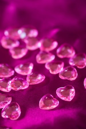 Many pink little crystal hearts on crimson satin fabric. Romantic card on St. Valentine's Day.の写真素材
