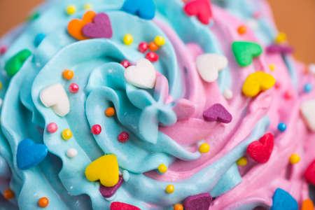 Closeup cupcake creamy multicolored top with colorful hearts and sprinkles. Romantic cake for Valentineâs dayの写真素材