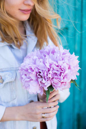 Young female hands holding beautiful tender bouquet of artificial pink peonies on mint green background. Spring bunch.の写真素材