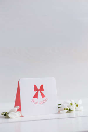 Bouquet of beautiful tender white snowdrops with greeting card on wooden background. Spring composition.の写真素材