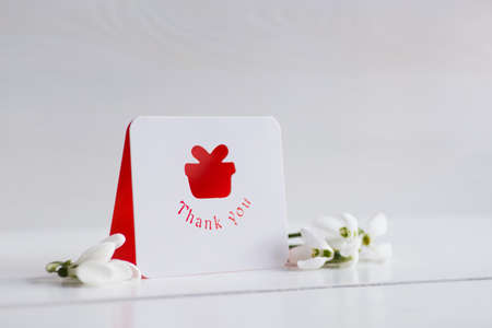 Bouquet of beautiful tender white snowdrops with greeting card on wooden background. Spring composition.の写真素材