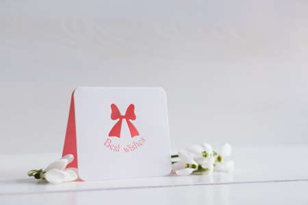 Bouquet of beautiful tender white snowdrops with greeting card on wooden background. Spring composition.の写真素材