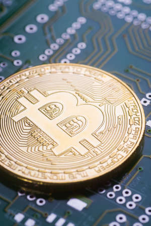 Golden bitcoin on green board with microchips and microcircuits on background. Concept of cryptocurrency, electronic payments and web banking.の写真素材