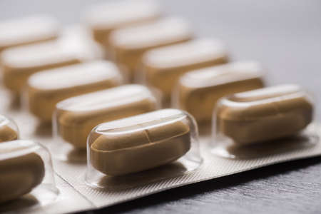 Closeup yellow long tablets in blister pack on gray background.の写真素材