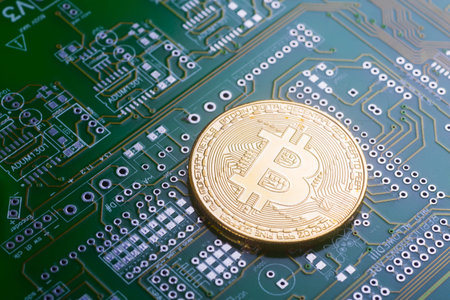 Golden bitcoin on green board with microchips and microcircuits on background. Concept of...