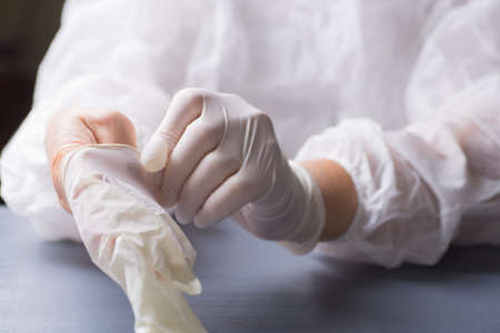 Surgeon puts on latex glove on his arm. Preparation of hands for surgery.の写真素材