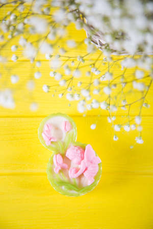 Decorative figure eight and fresh bouquet of white gypsophila on yellow wooden background. Concept of Women's day gift.の写真素材