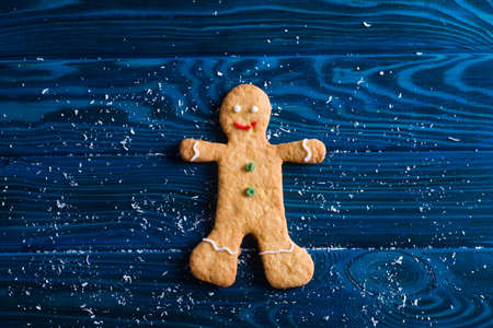 Closeup homemade Christmas cookies in form of gingerbread man on navy table. New Year baked biscuit.の写真素材