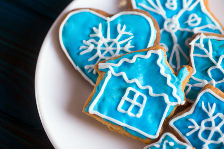 Closeup homemade Christmas glazed cookies with winter ornament on white plate. New Year biscuit in...