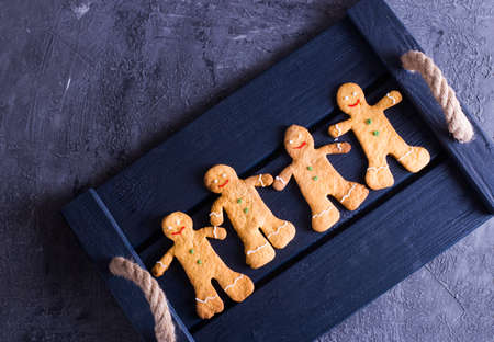Set of four baked gingerbread men on dark tray, flat lay. Concept of Christmas baking.の写真素材