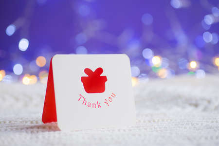 Thanksgiving Christmas greeting card on white knitted fabric on purple background with warm bokeh. New year card. Xmas decoration.の写真素材