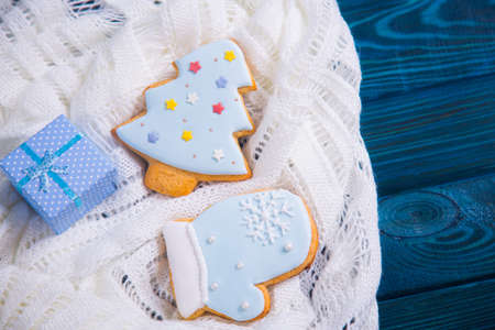 Christmas gingerbread decorated with icing and blue gift box on knitted white fabric. New Year homemade cookie.の写真素材