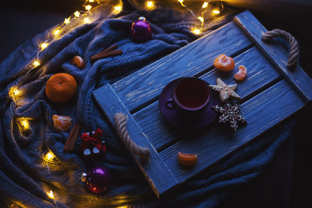 Fruit tea and Christmas homemade cookies on wooden tray surrounded by New Year decorations with...
