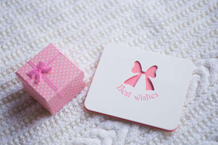 Greeting card with inscription "Best wishes" and pink gift box on white knitted fabric. New year card. Xmas decoration.の写真素材