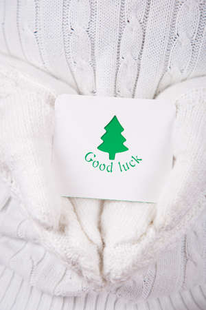 Hands in white knitted mittens holding greeting card with Christmas tree. Wishes of good luck. New Year card.の写真素材