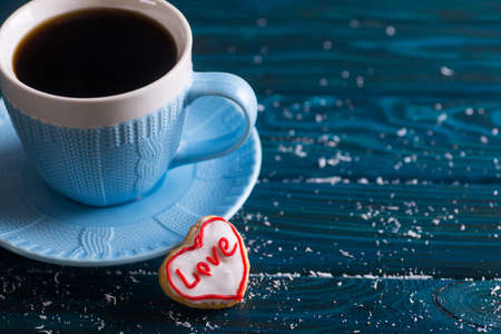Closeup homemade romantic glazed cookie in form of heart on table with cup of coffee. Valentine day gingerbread with icing.の写真素材