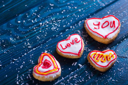 Closeup homemade romantic glazed cookie in form of hearts on navy wooden table. Valentine Day biscuit.の写真素材